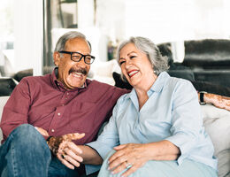 A couple laughing on a couch.