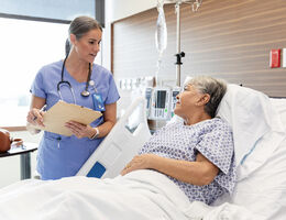 A patient in a hospital bed talks to a doctor.