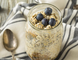 A jar of overnight oats with chia seeds, topped with blueberries.