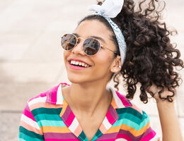 A girl wearing sunglasses and smiling.