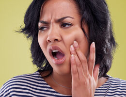 A woman rubs her jaw in pain.