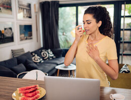 A woman uses a rescue inhaler.