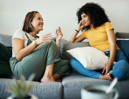 Two women, both smiling, share a conversation.