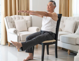 A man does chair exercises inside a home.