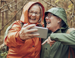 Two older women laugh while taking a selfie.